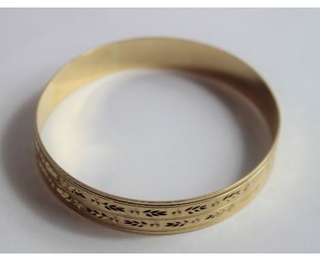 A 9ct gold solid bangle, flat profile with patterning throughout, 22.3mm wide, 19.95 grams gross