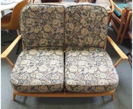 An Ercol two seater settee with light wood frame, stick back and original cushions