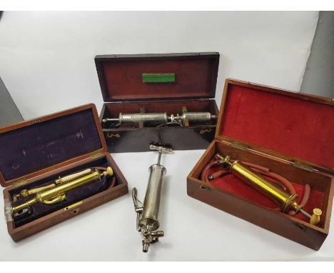 A vintage metal Arnold &amp; Sons syringe with accessories, contained in a stained wooden box; two brass syringes with access