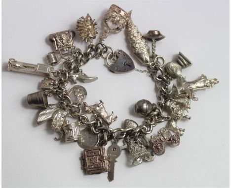 A silver chunky open curb link charm bracelet with heart padlock and safety chain, with various charms attached to include ar