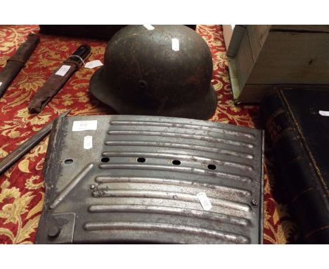 A German WWII anti-aircraft machine gun magazine and a German WWII helmet
