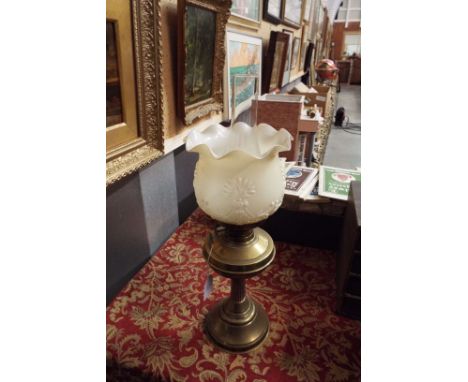 An early 20thC brass oil lamp with milk glass shade moulded in relief with floral swags