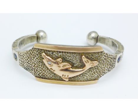 A heavy 925 silver bangle with 14ct gold applied fish decoration, set with a diamond and two sapphires, 90g