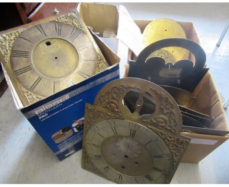 Three boxes containing a quantity of various brass dials and spares, together with a modern clock movement with spares 