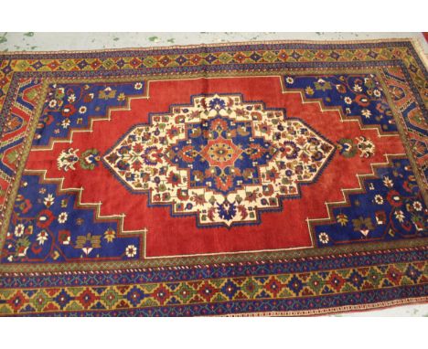 Turkish carpet with a lobed medallion and plain design with red ground, blue ground corner designs and polychrome borders, 33