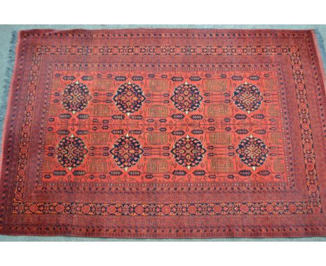 Modern Afghan Belouch carpet with two rows of four gols and an all-over stylised floral design on a wine ground with multiple