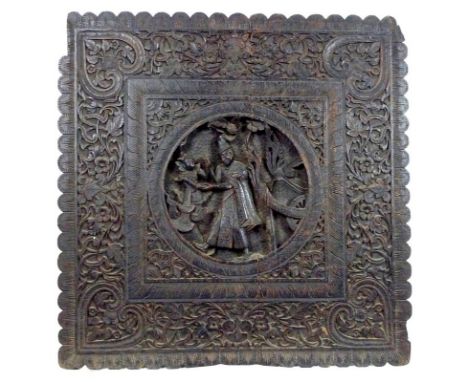 A 19th century oak panel, possibly South East Asian, carved in high relief with a central roundel depicting two figures and c
