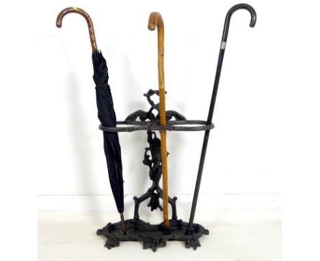 A cast iron Coalbrookdale style umbrella stand, together with a vintage black umbrella, a cane with a silver collar and a sti