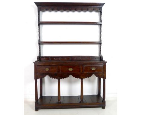 An early Georgian oak dresser and rack of small proportions, with stepped cornice over a shaped frieze fitted with eleven iro