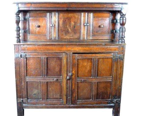 An early 18th century joined oak court cupboard, the upper section with a canopy frieze rail on turned side posts flanking th