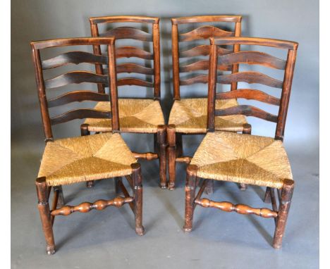 A Set of Four Early 19th Century Elm Ladder Backed Chairs with rush seats raised upon turned supports with stretchers 
