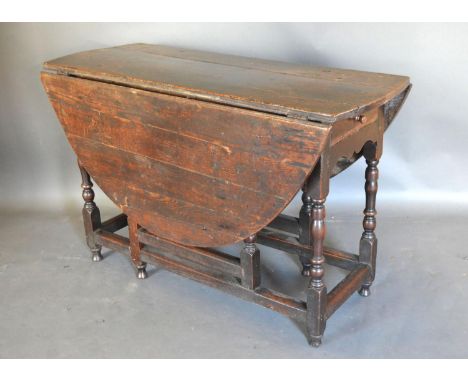 A George III Oak Oval Gate Legged Dining Table with a frieze drawer raised upon turned legs with stretchers 128cm x 107cm 