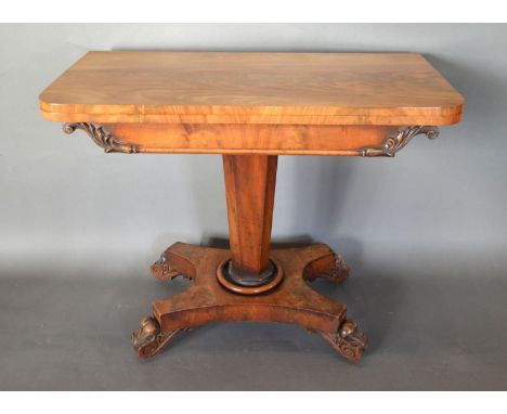 A William IV Mahogany Card Table the hinged top above a scroll carved frieze above an octagonal tapering centre column the qu