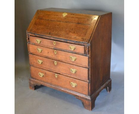A George III Oak Bureau with fall front enclosing a fitted interior with four drawers with brass handles and escutcheons rais