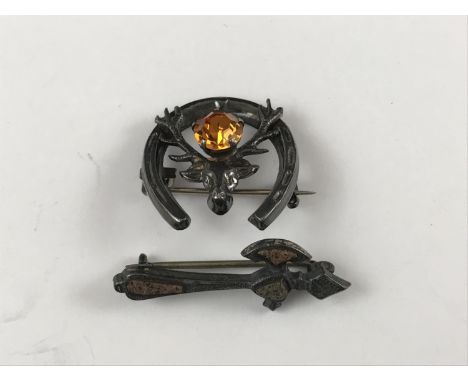 An early 20th Century Scottish style polished hardstone and silver brooch modelled as a battle axe, together with a white met