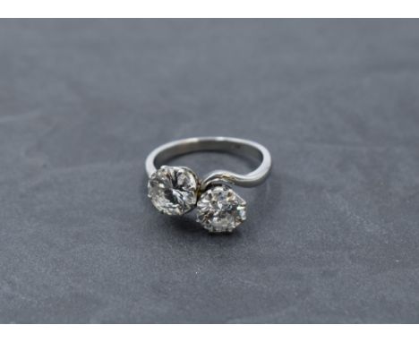 A diamond dress ring having a duo of diamonds, each approx 1.5ct in a claw set crossover mount on a white metal loop stamped 