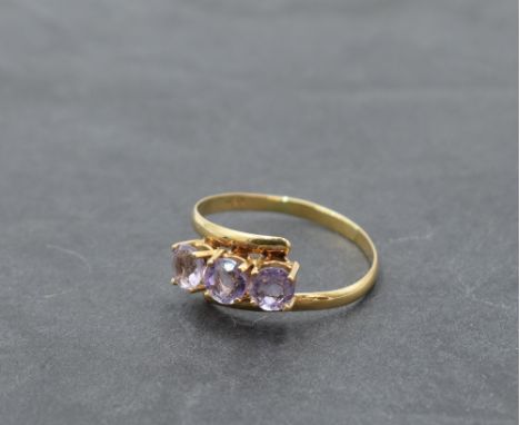 An amethyst trilogy ring having crossover shoulders on a yellow metal band stamped 18K, size R &amp; approx 1.9g