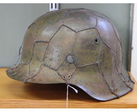 A WWII era German helmet (model 35) with camouflage paint work and wire netting still in place (a rare example)