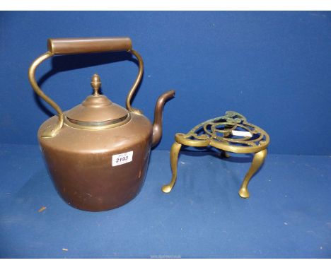 A copper kettle with acorn finial and a brass trivet.