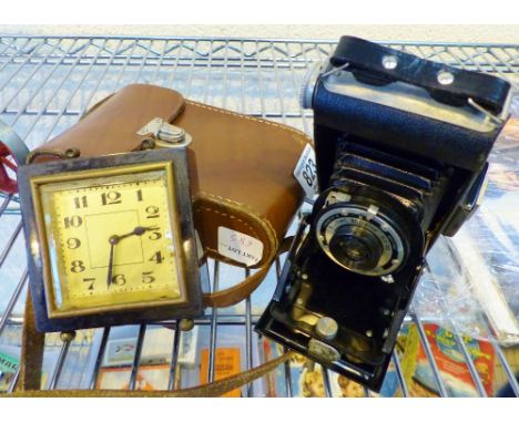 A folding Kodak bellows camera and a mechanical baklite alarm clock.