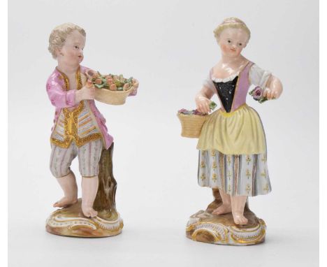 Pair of late 19th Century Meissen figures of a boy and girl, he proferring a single fruit in his left hand, with a basket of 
