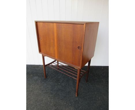 A teak cabinet on raised supports with under-shelf and fitted interior. 80cm x 46cm x 106cm 