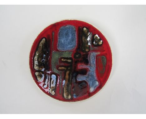 A Poole Delphis small dish with a blood red ground glaze, grey blue detail. Black back stamp. (Stained back) 12.5cm diameter
