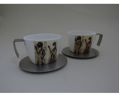 A pair of porcelain and stainless steel cups and saucers by "Art d'inox"
