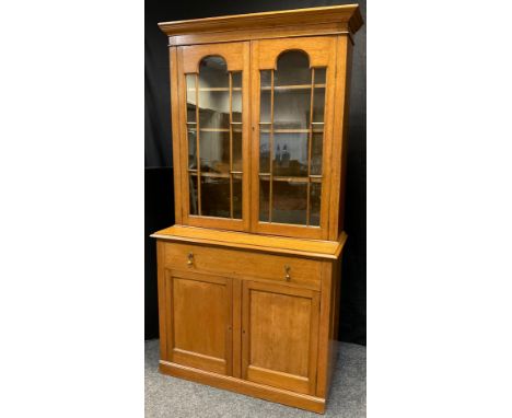 An early 20th century light oak bookcase cabinet, moulded cornice, pair of astral glazed doors enclosing three tiers of shelv