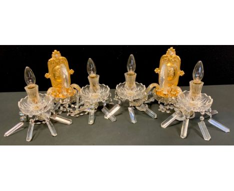 A pair of gilt metal and clear glass two light side wall lights, dished bowls, prismatic lustres, the lights divided by a spi