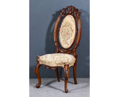 A 19th Century Walnut Framed Nursing Chair, oval back with fretted and carved framework, the seat and back upholstered in tap