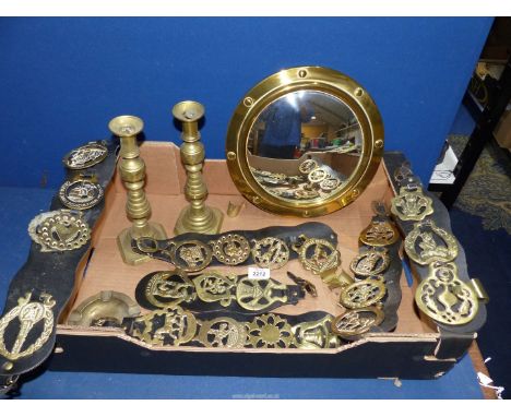 A quantity of brass including a pair of candlesticks [one pusher missing] martingales and a convex porthole mirror.