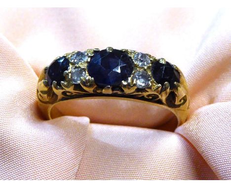 A stamped 18ct gold Engagement ring with three large dark blue sapphires and four diamond chips, size 'M', 4.76 gm.