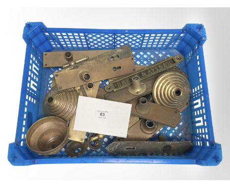 A crate of vintage brass door plates and a brass sign.