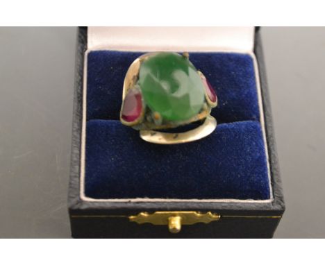 A green jade and red garnet cluster ring, oval faceted jade flanked by an inverted garnet to each side;  mixed metal mount, s