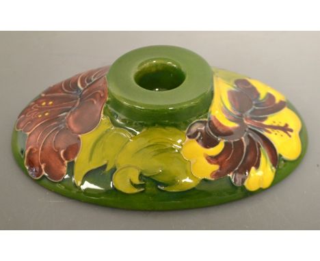 A Moorcroft Hibiscus pattern oval boudoir candlestick, tube lined with large flowerheads in red and yellow on a green ground,