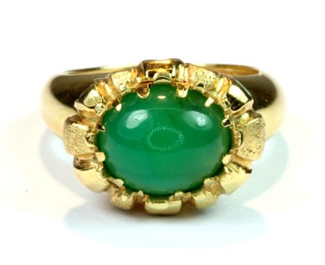 A heavy 18ct yellow gold (stamped 750) ring set with a large cabochon cut green stone, probably an emerald and set with emera