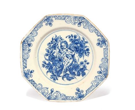 A delftware octagonal plate, c.1740-60, painted in blue with a bewigged putto or Cupid holding a flower spray among other flo