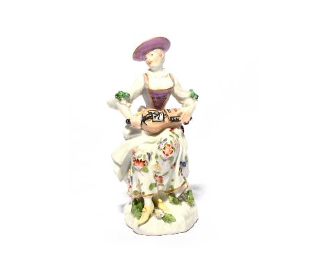 A Meissen figure of Columbine, mid 18th century, seated and playing the hurdy-gurdy, the instrument resting in her lap, weari