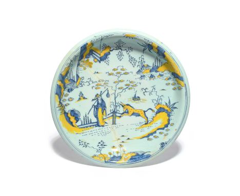 A large delftware charger, c.1700, possibly Bristol, painted in blue and yellow with a Chinese figure and a prancing kylin be