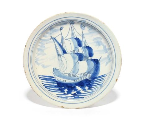 A rare delftware shipping plate, early 18th century, probably Bristol, painted in blue with a three masted ship at sail, with