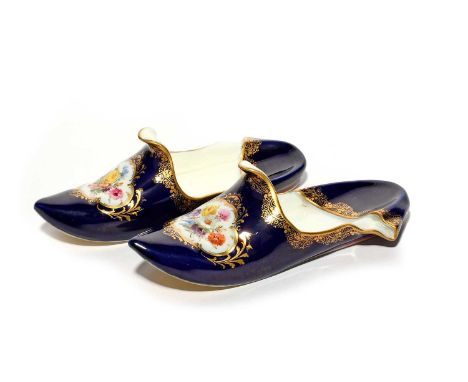 A pair of Meissen models of slippers, 19th/20th century, each painted with a panel of flowers reserved on a mazarin blue grou