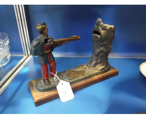 A CAST IRON MONEY BANK in the form of man firing at a tree trunk