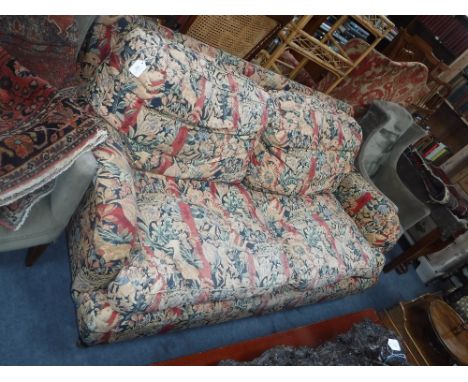 A VICTORIAN STYLE SOFA with broad and deep seat, with all over floral tapestry effect upholstery, on short legs with brass ca