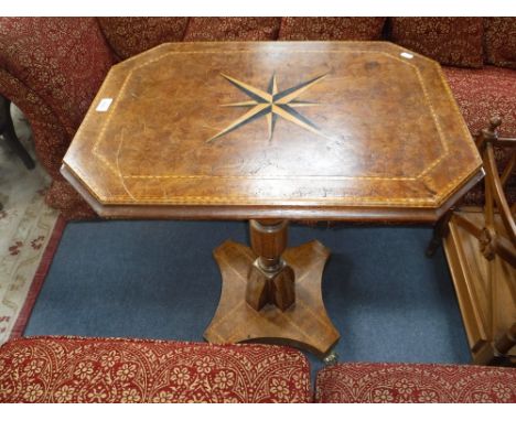 A CENTRE TABLE, inlaid with a compass point star against a burr veneer, on a shaped column base with all over conforming deco