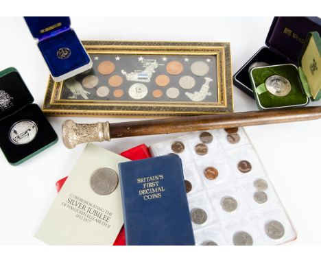 A collection of coins and a swagger stick, including several British crowns, a 2016 Royal Marines Commando coin in a case, a 