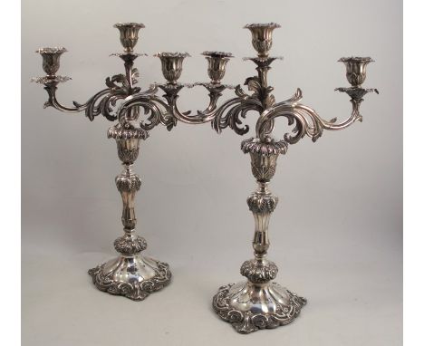 A pair of ornate rococco style silver plated three light candelabra, with scroll arms and raised on a trefoil shaped base, he