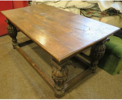 An Antique style oak refectory table, the rectangular top set with an inkwell, raised on heavily carved cup and cover legs un