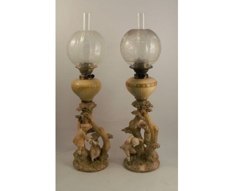 A pair of Royal Worcester blush ivory table lamps, in the Kate Greenaway style, decorated with children playing among tree st