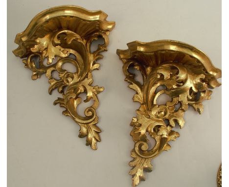 A pair of Italian gilt wood wall brackets, the shaped shelf supported by scrolling leaves, height 9.5ins